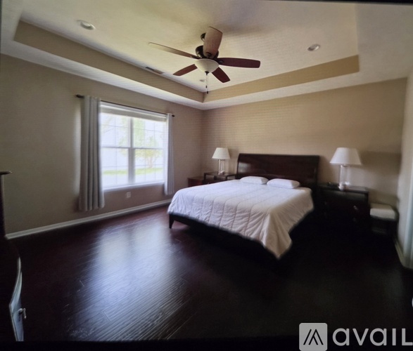 A bedroom with a bed, two lamps, and a ceiling fan.