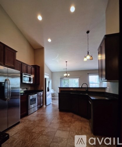 A kitchen with dark wood cabinets and a black countertop.