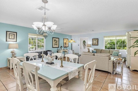 A dining room with a table set for six and a chandelier hanging from the ceiling.