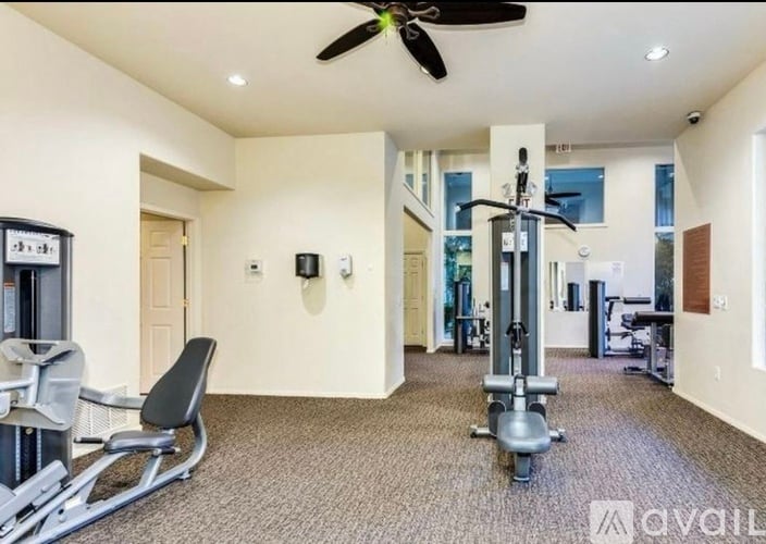 A gym room with a rowing machine and a fan.