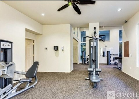 A gym room with a rowing machine and a fan.