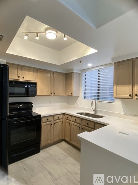 A kitchen with a black oven and wooden cabinets.