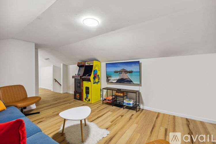 A living room with a yellow arcade machine and a painting of a mountain scene on the wall.