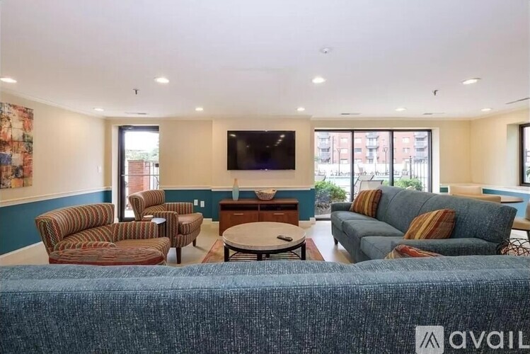 A living room with a blue couch and a television on the wall.