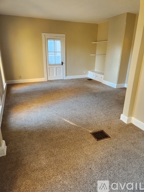 A room with a carpeted floor and a white door.