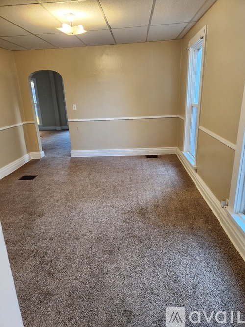 A carpeted room with a doorway leading to another room.