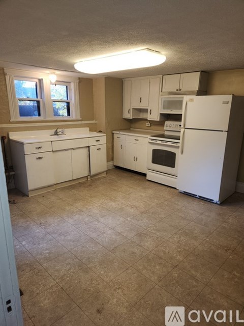 A kitchen with white appliances and a window.