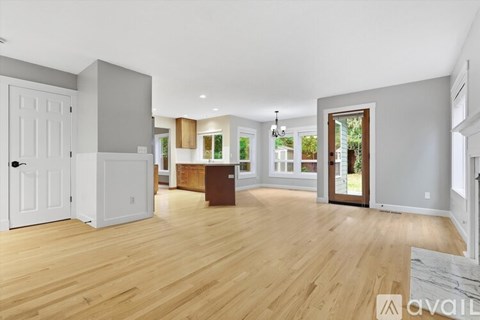 A spacious living room with wooden floors and a large window.