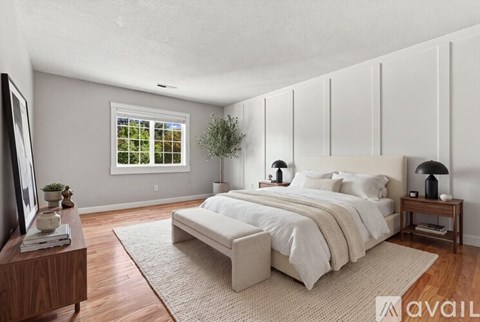 A bedroom with a large bed, a window, and a television.