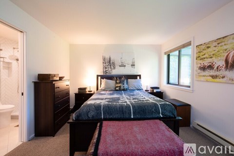 A bedroom with a large bed, a dresser, and a painting on the wall.