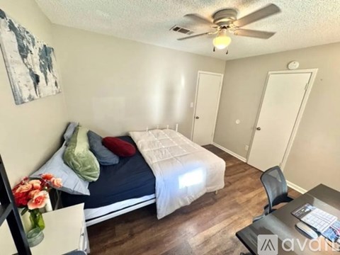 A bedroom with a bed, chair, and painting on the wall.
