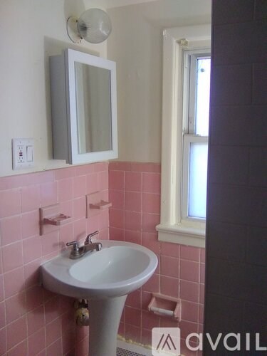 A bathroom with pink tiles and a white pedestal sink.
