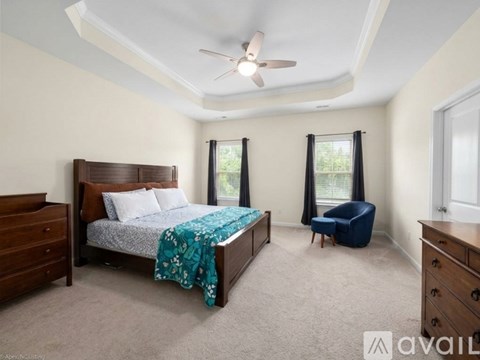 A bedroom with a bed, chair, and ceiling fan.