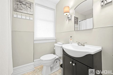 A bathroom with a toilet, sink, and mirror.