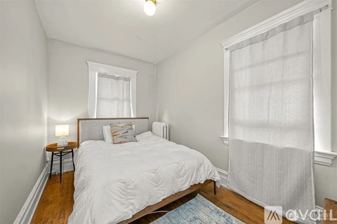 A bedroom with a bed, nightstand, and window.