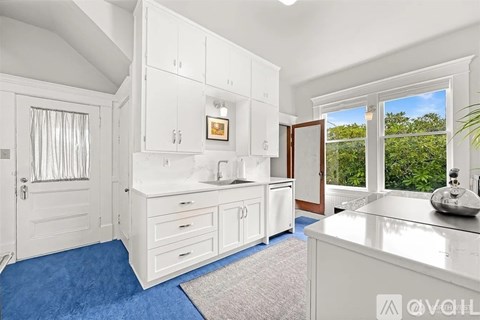 A kitchen with white cabinets and a blue carpet.