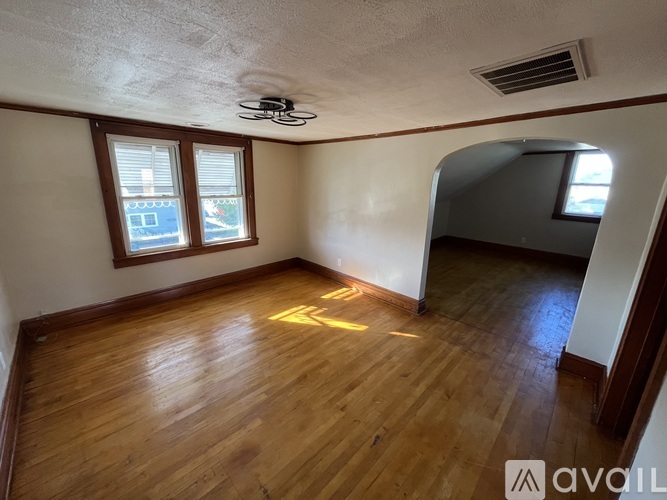 A room with wooden floors and a window with blinds.