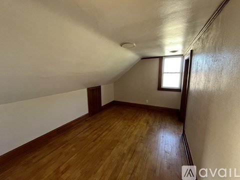 A room with wooden floors and a window on the right side.