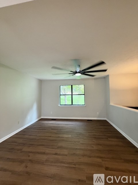 A room with a ceiling fan and wooden flooring.