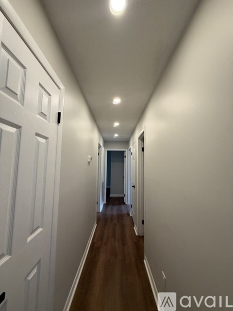 A long hallway with white walls and wood floors.