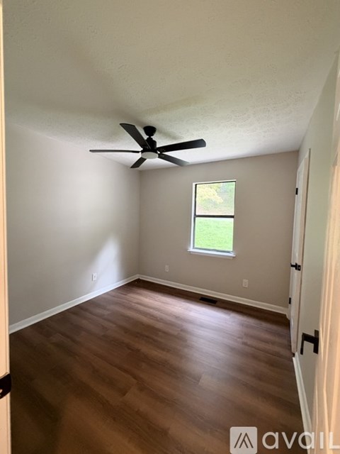 A room with a ceiling fan and wooden flooring.