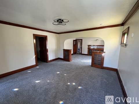 A spacious room with a carpeted floor and a ceiling fan.