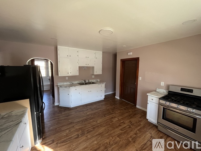 A kitchen with wooden floors and white appliances is available for rent.