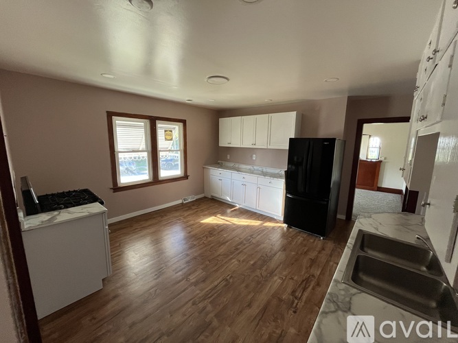 A kitchen with wooden floors and a black refrigerator.