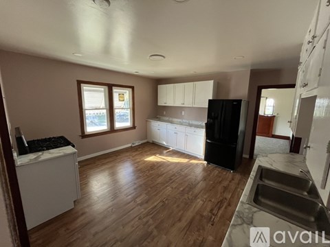 A kitchen with wooden floors and a black refrigerator.