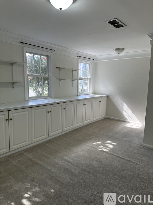 A room with white walls and a window with a view of trees.