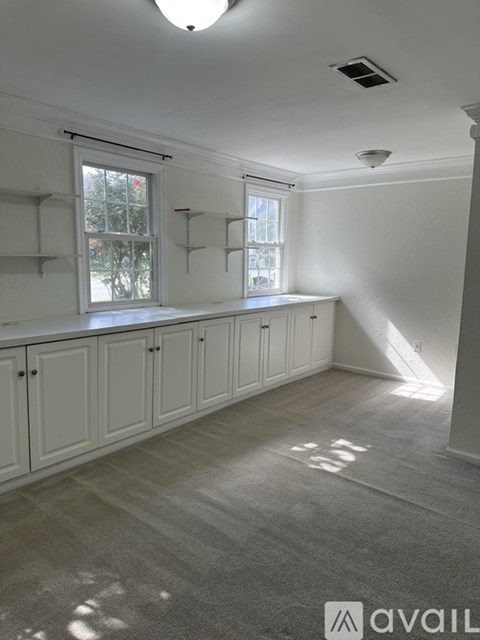 A room with white walls and a window with a view of trees.