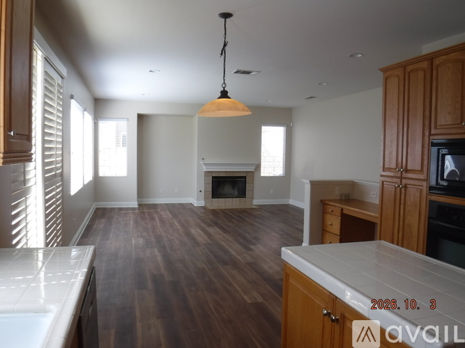 A well-lit kitchen with wooden cabinets and a white countertop.