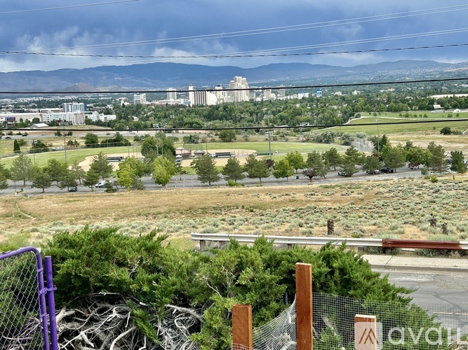 A view of a city from a hill with buildings and greenery in the foreground.