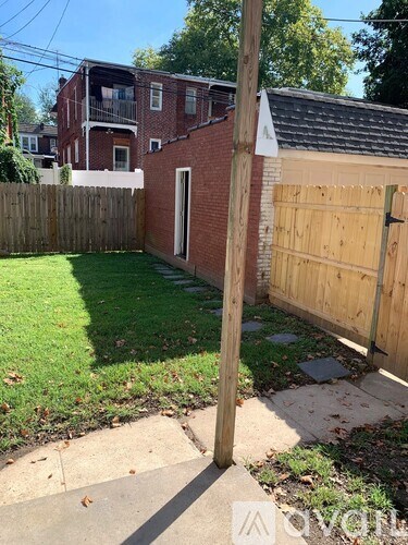 A backyard with a wooden fence and a brick building in the background.