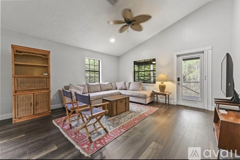 A living room with a sofa, a chair, a rug, and a television.