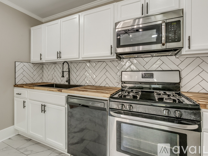 A kitchen with white cabinets and a black and white tiled backsplash.