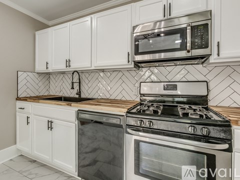A kitchen with white cabinets and a black and white tiled backsplash.