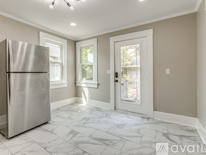 A kitchen with a refrigerator, tiled floor, and a door leading outside.
