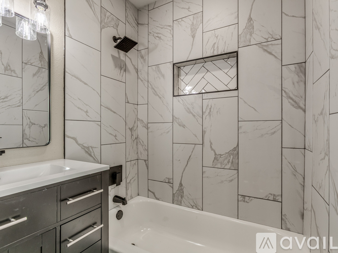A bathroom with a marble tile wall and a white bathtub.