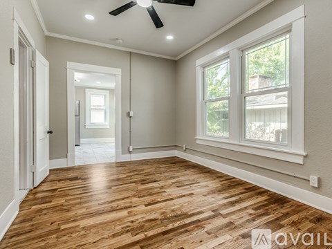 A spacious room with wooden flooring and a ceiling fan.