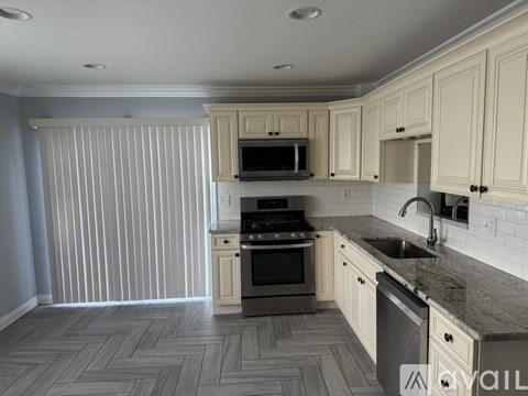 A kitchen with a sink, stove, and microwave.