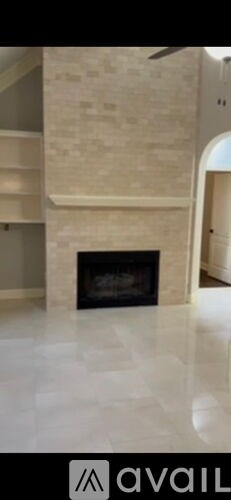 A spacious living room with a fireplace and a fan.