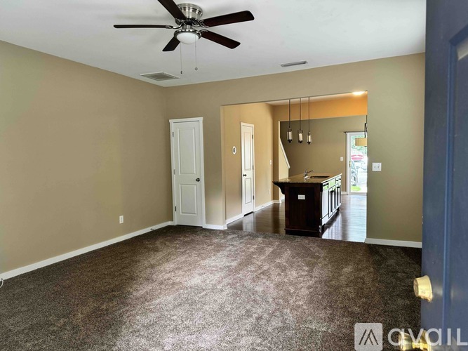A spacious room with a ceiling fan and carpeted floor.