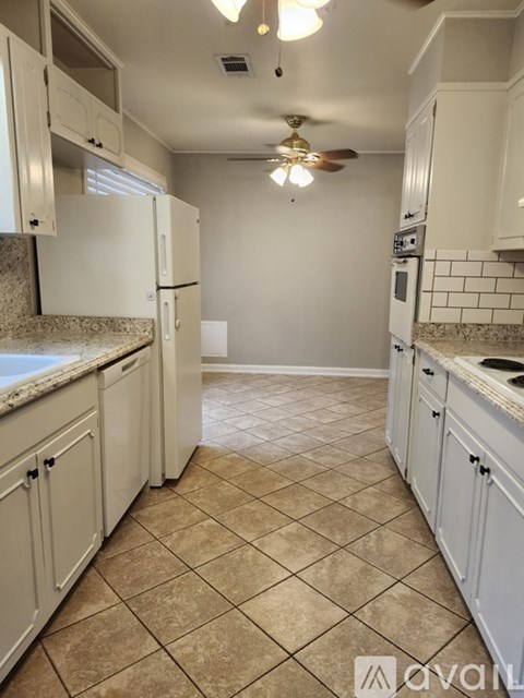 A kitchen with white cabinets and a tiled floor.