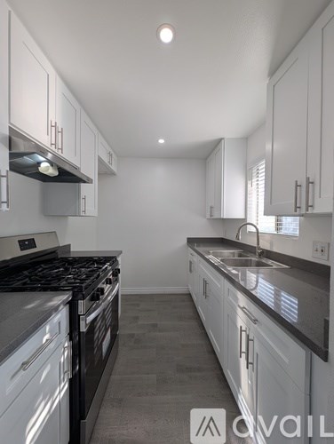 A kitchen with white cabinets and a black stove top.