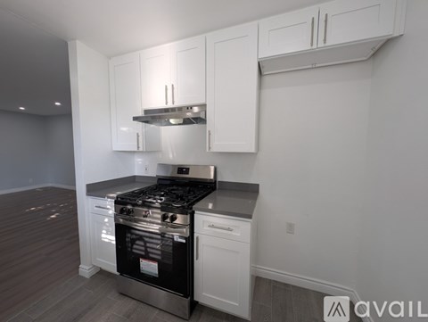 A kitchen with white cabinets and a stainless steel stove top.