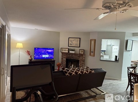 A living room with a fireplace and a television on.