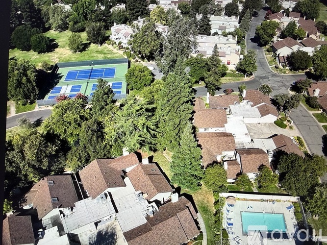 A bird's eye view of a neighborhood with a tennis court and a pool.