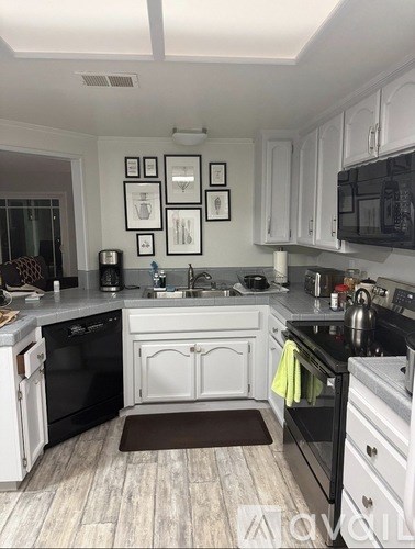 A kitchen with black appliances and white cabinets.