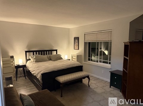 A bedroom with a large bed and a window with blinds.